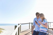 Couple on boardwalk using cell phone — Stock Photo