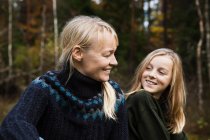 Smiling mother and daughter in forest — Stock Photo