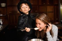 Girl tasting magician boy cooking — Stock Photo