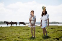 Girls in costumes on grassy shore — Stock Photo