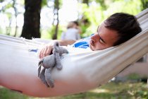 Мужчина спит в гамаке с игрушкой — стоковое фото