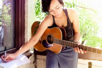 Femme écrivant de la musique avec guitare — Photo de stock