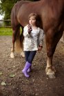 Fille tenant brosse près du cheval — Photo de stock