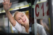 Mujer saludando adiós desde la ventana - foto de stock
