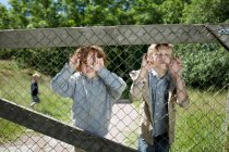 Meninos espreitando através de cerca de corrente — Fotografia de Stock