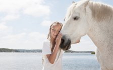 Девушка ласкает лошадь на пляже — стоковое фото