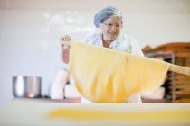 Mature chef rolling dough — Stock Photo