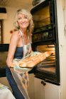 Femme tenant boulangerie dans la cuisine — Photo de stock