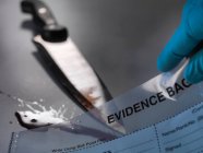 Knife and hand holding evidence bag — Stock Photo