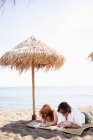 Paar liest unter Sonnenschirm — Stockfoto