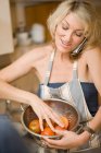 Mujer cocinando y usando teléfono - foto de stock