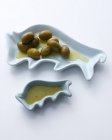 Green olives and olive oil in dishes — Stock Photo