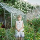 Маленька дівчинка стоїть біля теплиці — стокове фото
