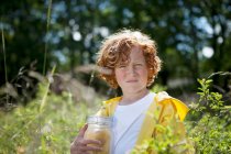 Boy holding jar in field of tall grass — Stock Photo