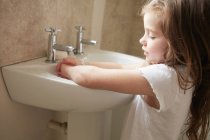 Girl washing hands in bathroom — Stock Photo