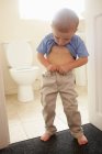 Хлопчик натискає свої штани у ванній — стокове фото