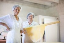 Trainee with chef holding rolling pin — Stock Photo