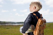 Niño llevando tarro en campo herboso - foto de stock