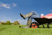Man in rubber boots sitting in wheelbarrow — Stock Photo