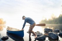 Homem empurrando canoa — Fotografia de Stock