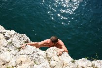 Hombre escalando cara de roca empinada - foto de stock