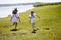 Девушки бегут по травянистому берегу реки — стоковое фото
