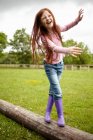 Lächelndes Mädchen balanciert auf Holzstämmen — Stockfoto