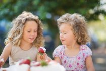Girls eating strawberries outdoors — Stock Photo