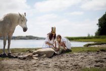 Girls petting horse on sandy beach — Stock Photo