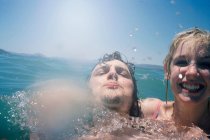 Sorridente coppia spruzzi in mare — Foto stock