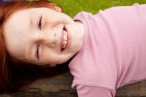 Lächelndes Mädchen, das auf Holzklotz liegt — Stockfoto