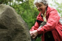 Жінка зв'язує взуття на скелі — стокове фото