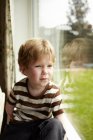 Хлопчик дивиться у вікно на задньому дворі — стокове фото