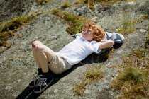 Ragazzo posa su roccia erbosa — Foto stock