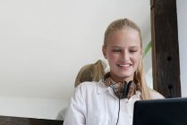 Mujer sonriente con auriculares usando laptop - foto de stock