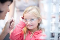 Молодая девушка примеряет очки — стоковое фото