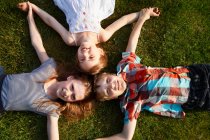 Crianças deitadas na grama juntas — Fotografia de Stock