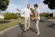 Отец и сын играют со скейтбордом, избирательный фокус — стоковое фото
