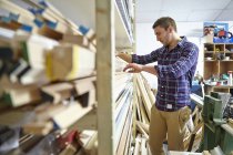 Mid adult man searching stockroom shelves in picture framers workshop — Stock Photo