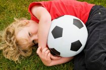 Menino segurando bola de futebol na grama — Fotografia de Stock
