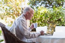 Older man using laptop outdoors — Stock Photo