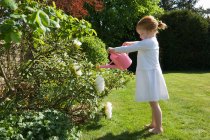 Mädchen gießt Blumen im Hinterhof — Stockfoto