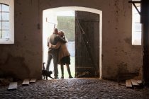 Casal abraçando em portas do celeiro, vista traseira — Fotografia de Stock
