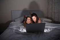 Madre e hija usando laptop en la cama - foto de stock