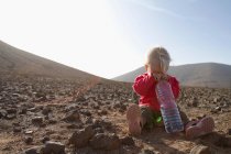 Toddler with bottle of water in desert — Stock Photo