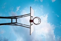 Basketball hoop under blue cloudy sky, low angle view — Stock Photo