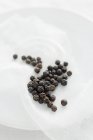 Black peppercorns and gauze on plate — Stock Photo