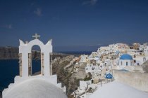 Vista del campanario de la iglesia lavada blanca y la ciudad, Oia, Santorini, Cícladas, Grecia - foto de stock