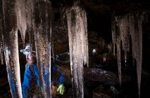Senderista con carámbanos en cueva glacial - foto de stock