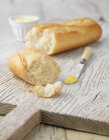 Baguete branco com manteiga na tábua de madeira branca — Fotografia de Stock